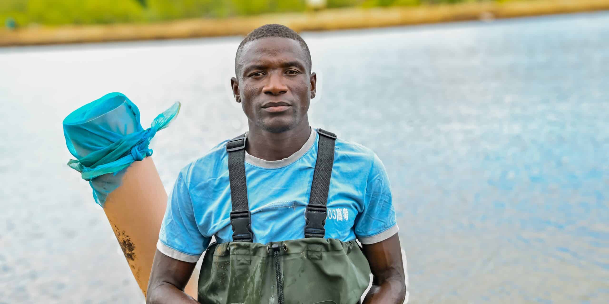 young man in fishing waders with lake or pond in background